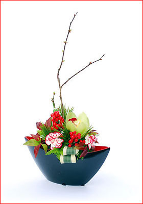 お正月らしい洋蘭と枝松、梅枝、千両などの花材と舟形の器に活けたフラワーアレンジ